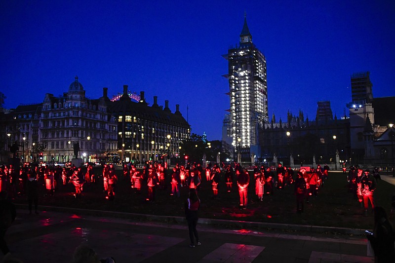 Backdropped by parliament, demonstrators hold a silent vigil in Parliament Square to rise awareness on entertainment and arts world, in London, Saturday, Oct. 31, 2020. Backstage technicians and crews are calling for more fundingfrom the government for the performing arts and hospitality sectors as the coronavirus lockdown is widely anticipated to be extended in England to help control the spread of COVID-19. (AP Photo/Alberto Pezzali)