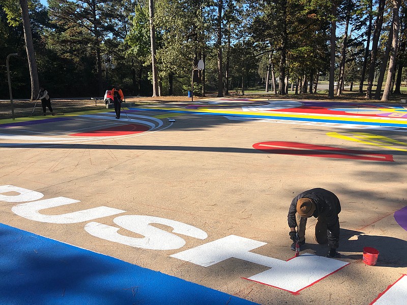 A team of young professionals and artists work on a Lakwena-inspired mural at the Martin Luther King Jr. Park basketball court. (Special to The Commercial)