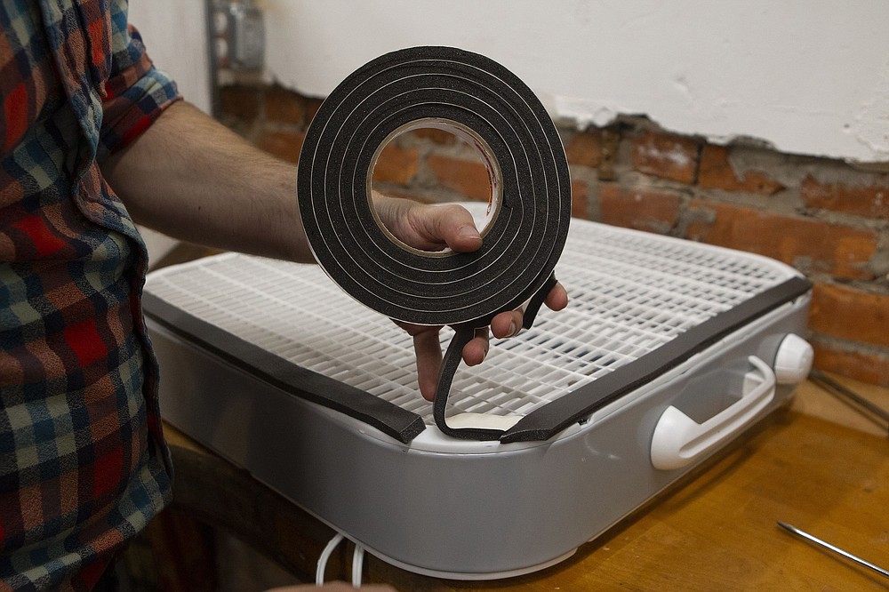 Adhesive insulation is put to box fan to create a seal. Tom Meyer, President of Hive76, and Inquirer writer Tom Avril demonstrate how to build an air filtering system out of a box fan and some furnace filters.
(TNS/Charles Fox/The Philadelphia Inquirer)