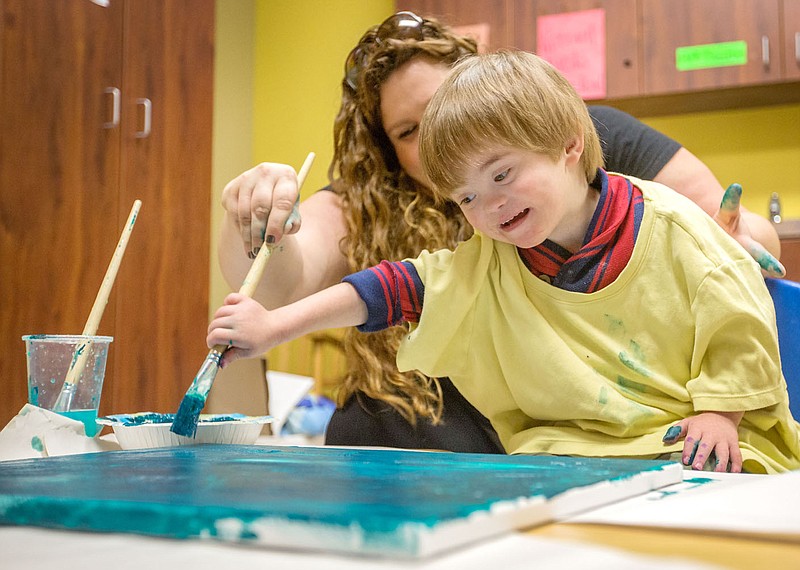 NWA Media/JASON IVESTER --11/06/2014--
Leigh Kate Ochieng (cq) helps Finley Owen, 4, with his class' painting on Thursday, Nov. 6, 2014, at the Sunshine School in Little Flock. The students are preparing Frozen-themed art pieces for the the school's annual Very Special Art Show on Nov. 14. story.lead_photo.caption