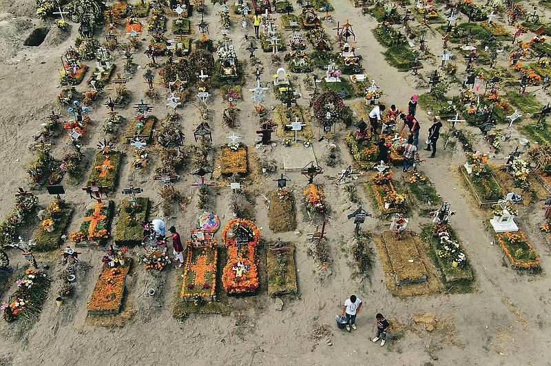 People visit the graves of their relatives buried at the Valle de Chalco municipal cemetery, some decorated ahead of the Day of the Dead holiday, on the outskirts of Mexico City, Thursday, Oct. 29, 2020. Mexico's Day of the Dead celebration this weekend won't be the same in a year so marked by death, in a country where more than 90,000 people have died of COVID-19. (AP Photo/Fernando Llano)