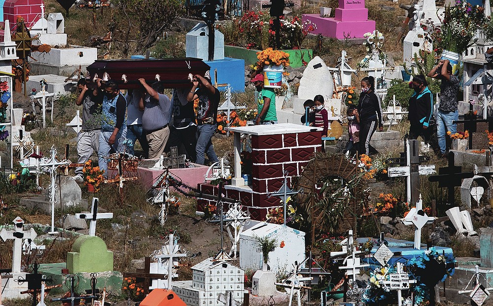 People carry the coffin that contains the remains of a relative at the Valle de Chalco Municipal Cemetery on the outskirts of Mexico City, Saturday, Oct. 31, 2020. Mexico’s Day of the Dead celebration this weekend won’t be the same in a year so marked by death after more than 90,000 people have died of COVID-19. (AP Photo/Marco Ugarte)