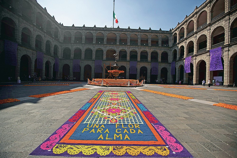 A patio inside the presidential palace is decorated with the traditional colors of Day of The Dead, with the Spanish message "A flower for each soul," in Mexico City, Saturday, Oct. 31, 2020. The holiday isn't the same in a year so marked by death in a country where more than 90,000 people have died of COVID-19, many cremated rather than buried and with cemeteries forced to close. (AP Photo/Fernando Llano)