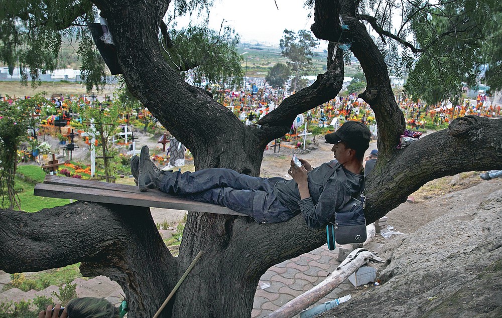 A man who works decorating graves for Day of the Dead waits for visitors to Valle de Chalco municipal cemetery on the outskirts of Mexico City, Saturday, Oct. 31, 2020. Mexico’s Day of the Dead celebration this weekend won’t be the same in a year so marked by death after more than 90,000 people have died of COVID-19. (AP Photo/Marco Ugarte)