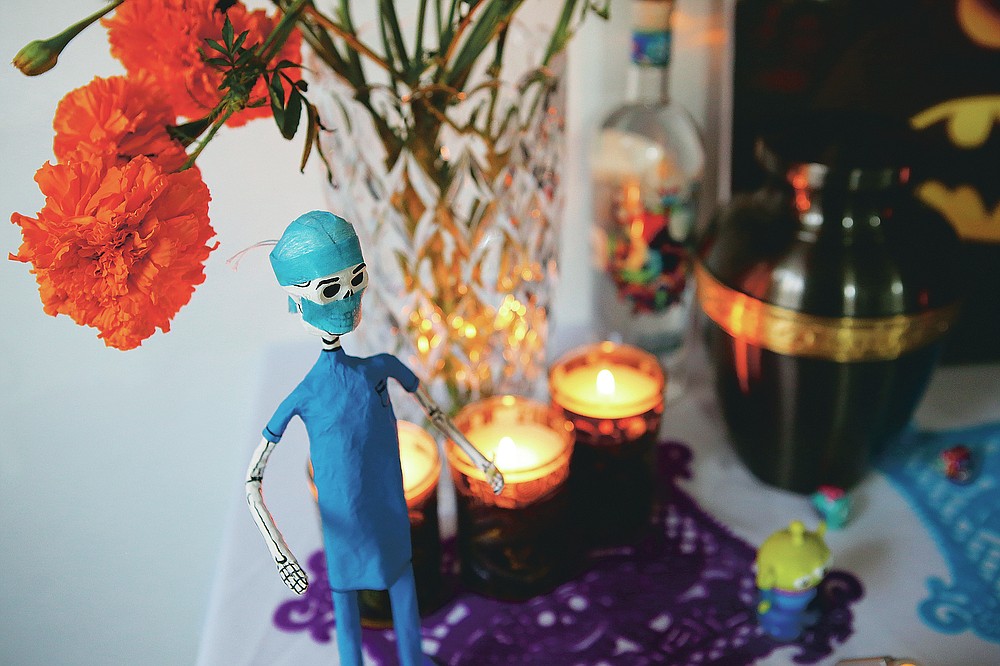 A paper skeleton dressed as a doctor adorns a Day of the Dead altar for Daniel Silva Montenegro, a doctor who died from symptoms related to COVID-19, made by his wife Kenya Navidad at her home in Mexico City, Saturday, Oct. 31, 2020. The weekend holiday isn't the same in a year so marked by death in a country where more than 90,000 people have died of COVID-19, many cremated rather than buried and with cemeteries forced to close. (AP Photo/Ginnette Riquelme)