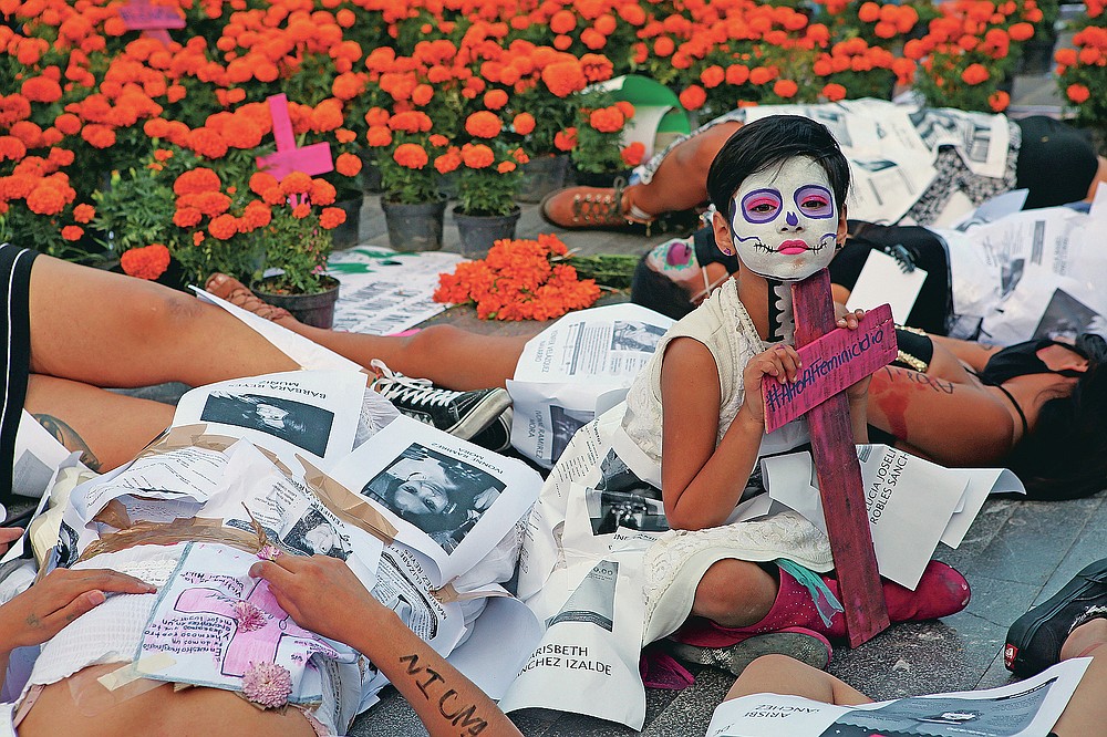 A girl is surrounded by women dressed as "Catrinas" during a performance to demand justice for victims of femicide on Day of the Dead in Mexico City, Sunday, Nov. 1, 2020. (AP Photo/Ginnette Riquelme)