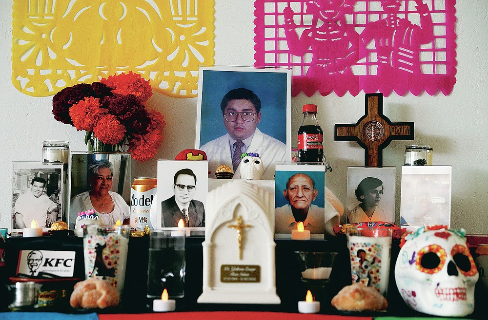 A portrait of Dr. Guillermo Flores, who died from symptoms related to COVID-19, is placed on a Day of the Dead altar made by his wife, Alexandra Valverde, at their home in Mexico City, Sunday, Nov. 1, 2020. He is one of more than 1,700 Mexican health workers officially known to have died of COVID-19 who are being honored with three days of national mourning on these Days of the Dead. (AP Photo/Eduardo Verdugo)