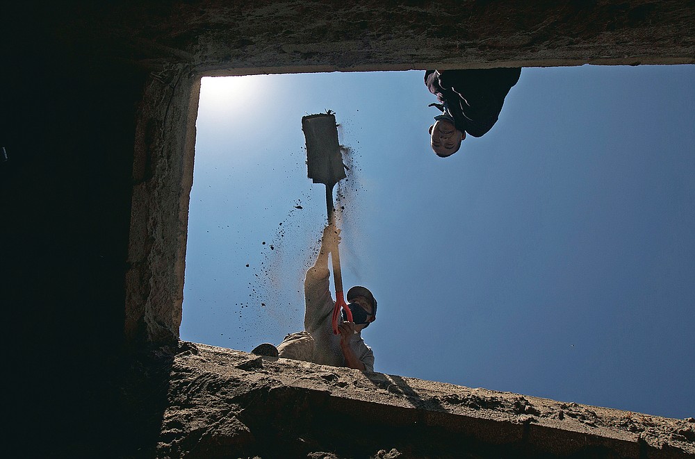 Seen from the bottom, workers clean a grave after removing a coffin to replace it with another on Day of the Dead at the Valle de Chalco Municipal Cemetery on the outskirts of Mexico City, Monday, Nov. 2, 2020. Mexico's Day of the Dead celebration isn't the same in a year so marked by death after more than 90,000 people have died of COVID-19. (AP Photo/Marco Ugarte)