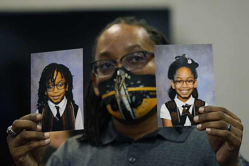 FILE - In this Tuesday, Oct. 27, 2020, file photo, Sheldon Smith, center, holds the photographs of his children Deshawn Smith, 11, left, and Trinitee Smith, 13, both suffering from sickle cell anemia, during an Initiative 65 rally in Ridgeland, Miss. Smith and his wife Keishawna Smith believe their children would benefit from medical marijuana treatment for pain management. Initiative 65 would amend the Mississippi Constitution to allow the prescription by a doctor of up to 5 ounces (142 grams) of marijuana per month for people who suffer from more than 20 medical conditions. The state lawmakers are offering a more restrictive measure as an alternative. (AP Photo/Rogelio V. Solis, File)