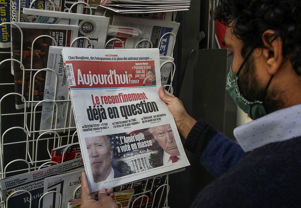 A man wearing a face mask as a precaution against the coronavirus reads the headlines about the U.S. presidential elections at a newspapers stand in Paris, Wednesday, Nov. 4, 2020. The world is watching as millions of Americans cast their ballots for the next president on Tuesday. (AP Photo/Michel Euler)