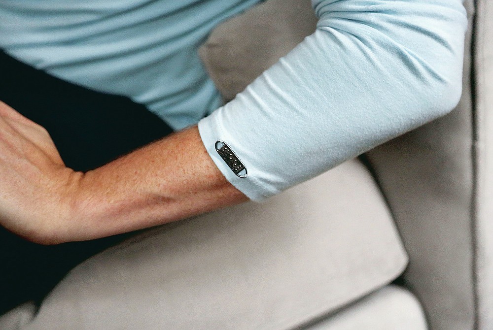 A metal tag reading "feel" in braille is stitched to the left arm of Bradford Manning's long sleeve shirt produced by their company Two Blind Brothers, in New York City on Friday, Oct. 23, 2020. The brothers have raised more than $700,000, which they've donated to preclinical research trials to help cure blindness. (AP Photo/Jessie Wardarski)