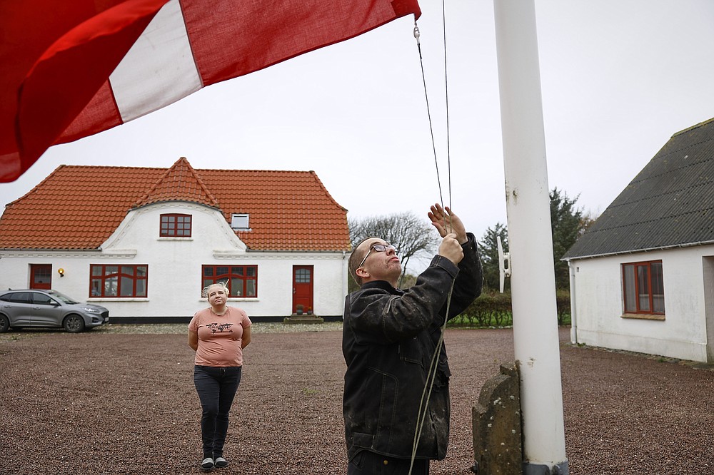 Peter and Trine Brinkmann Nielsen put their flag to halfmast at the Norden mink farm, after the government called for the culling of minks, in Boerglum Kloster, Denmark. Thursday, Nov. 5,  2020.  Denmark's prime minister says the government wants to cull all 15 million minks in Danish farms, to minimize the risk of them re-transmitting the new coronavirus to humans. She said Wednesday, Nov. 4, 2020, a report from a government agency that maps the coronavirus in Denmark has shown a mutation in the virus found in 12 people in the northern part of the country who got infected by minks. (Claus Bjoern Larsen/Ritzau Scanpix via AP)