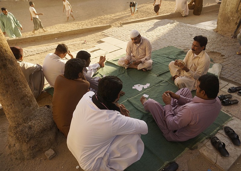 FILE - In this Jan. 24, 2020 file photo, workers play cards during their holiday in the Old City of Jiddah, Saudi Arabia.  On Wednesday, Nov. 4, 2020, Saudi Arabia, announced reforms that will abolish some key restrictions tying millions of low-paid and vulnerable migrant workers to their employers in conditions that have been rife with abuse and exploitation. (AP Photo/Amr Nabil, File)