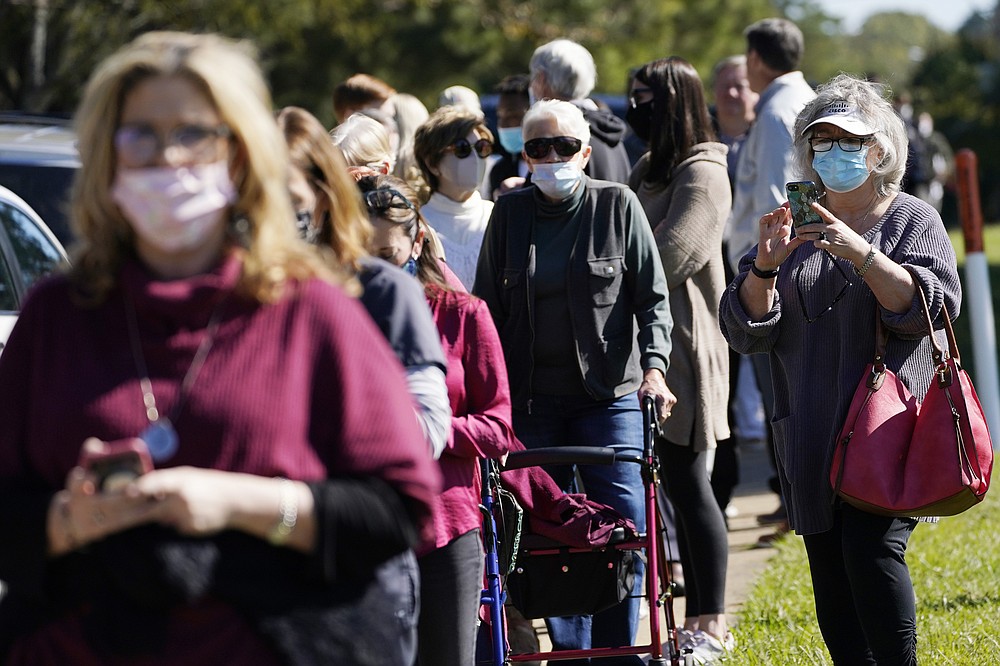 A voter records the long line of people waiting to cast their ballot at Precinct 45 in Jackson, Miss., Tuesday, Nov. 3, 2020. (AP Photo/Rogelio V. Solis)