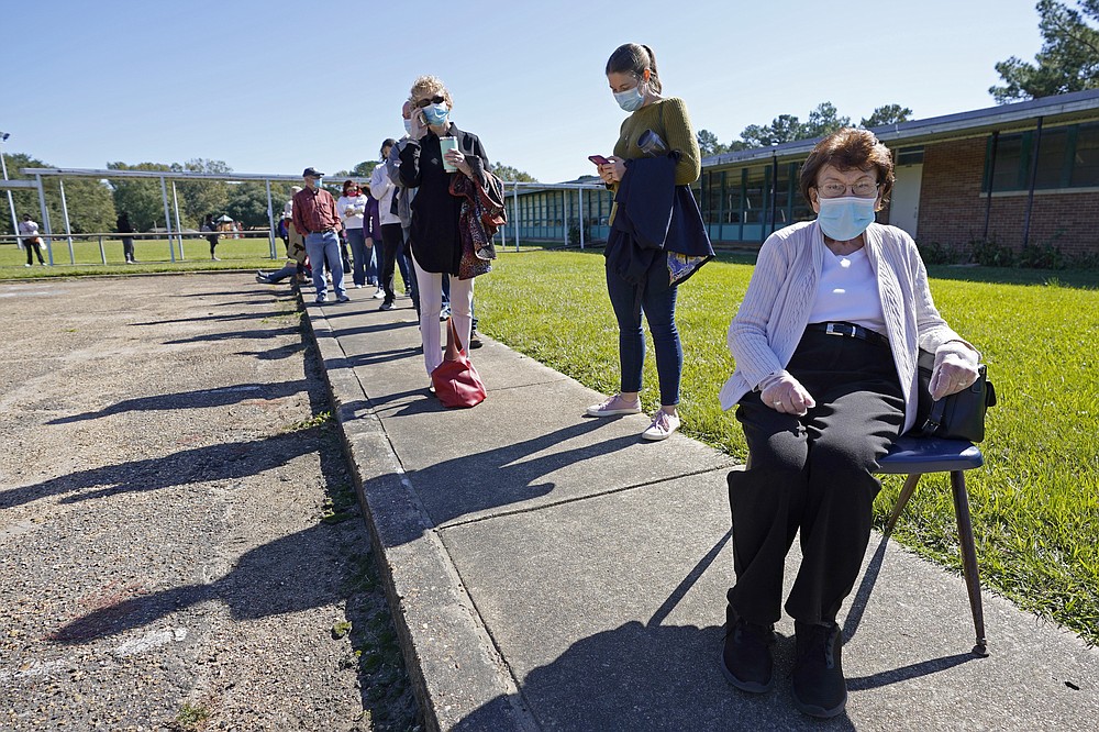 Nancy Cross admitted to feeling guilty to "borrowing" a chair from the student pick up line outside McLeod Elementary School as she waited in line to vote for over two hours to cast her ballot in the general election in Jackson, Miss., Tuesday, Nov. 3, 2020. (AP Photo/Rogelio V. Solis)