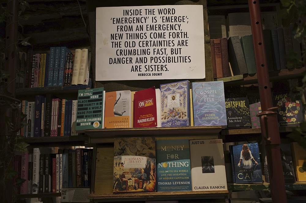 A panel on "Emergency" by Rebecca Solnit hangs on the book shelves of the English and American literature Shakespeare and Co. bookstore, in Paris, France, Thursday, Nov. 05, 2020. Iconic Parisian bookshop Shakespeare and Co. has launched a support appeal to its readers after its owners say that coronavirus-linked losses, and a crippling months-long lockdown, have left the future of the veritable institution in doubt. "We've been minus 80 percent since the first confinement in March, so at this point we've used all our savings," Sylvia Whitman, daughter of the shop's co-founder George Whitman, told the Associated Press. (AP Photo/Francois Mori)