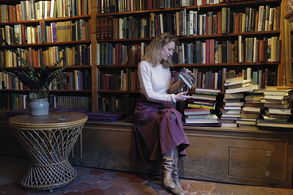 Sylvia Whitman, proprietor of the English and American literature Shakespeare and Co. bookstore, sorts books in her shop in Paris, France, Thursday, Nov. 05, 2020. Iconic Parisian bookshop Shakespeare and Co. has launched a support appeal to its readers after its owners say that coronavirus-linked losses, and a crippling months-long lockdown, have left the future of the veritable institution in doubt. "We've been minus 80 percent since the first confinement in March, so at this point we've used all our savings," Sylvia Whitman, daughter of the shop's co-founder George Whitman, told the Associated Press. (AP Photo/Francois Mori)
