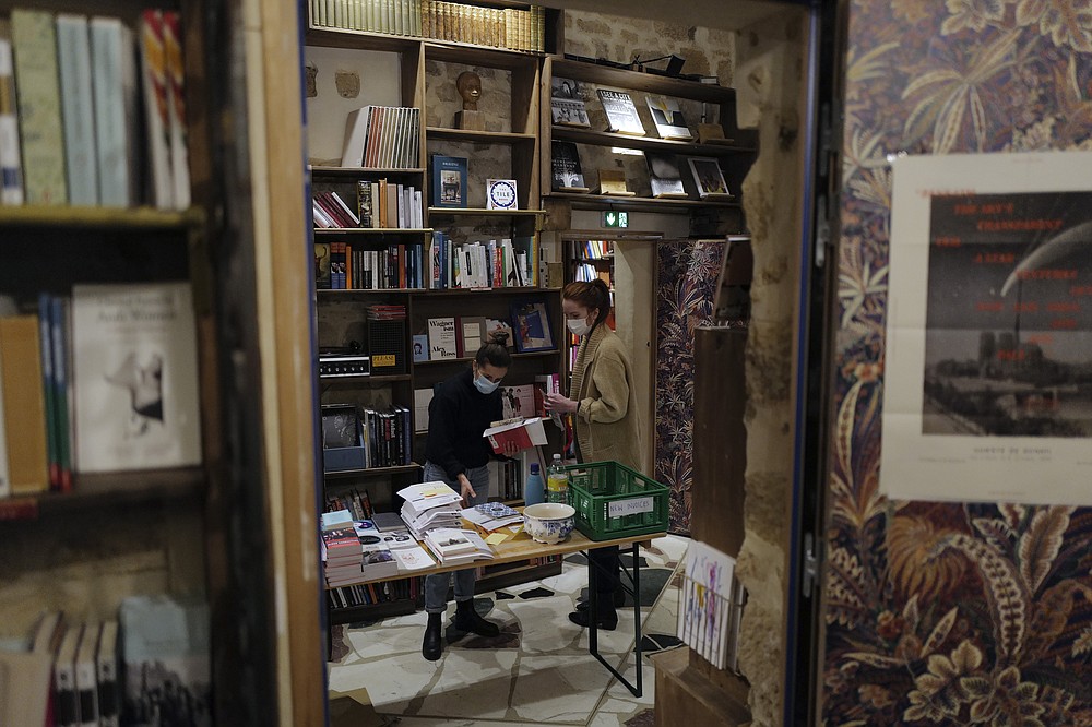 Employees sort books in the English and American literature Shakespeare and Co. bookstore, in Paris, France, Thursday, Nov. 05, 2020. Iconic Parisian bookshop Shakespeare and Co. has launched a support appeal to its readers after its owners say that coronavirus-linked losses, and a crippling months-long lockdown, have left the future of the veritable institution in doubt. "We've been minus 80 percent since the first confinement in March, so at this point we've used all our savings," Sylvia Whitman, daughter of the shop's co-founder George Whitman, told the Associated Press. (AP Photo/Francois Mori)
