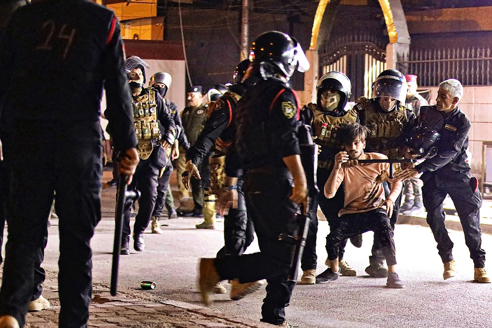 Riot police arrest a protester while security forces prevent anti-government protesters from setting up sit in tents in Basra, Iraq, Friday, Nov. 6, 2020. (AP Photo/Nabil al-Jurani}