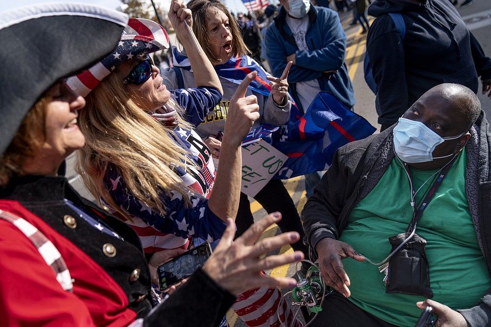 A Biden supporter who would only give his first name, Douglas, right, engages in a debate with Trump supporters demonstrating against the election results outside the central counting board at the TCF  Center in Detroit, Friday, Nov. 6, 2020. (AP Photo/David Goldman)