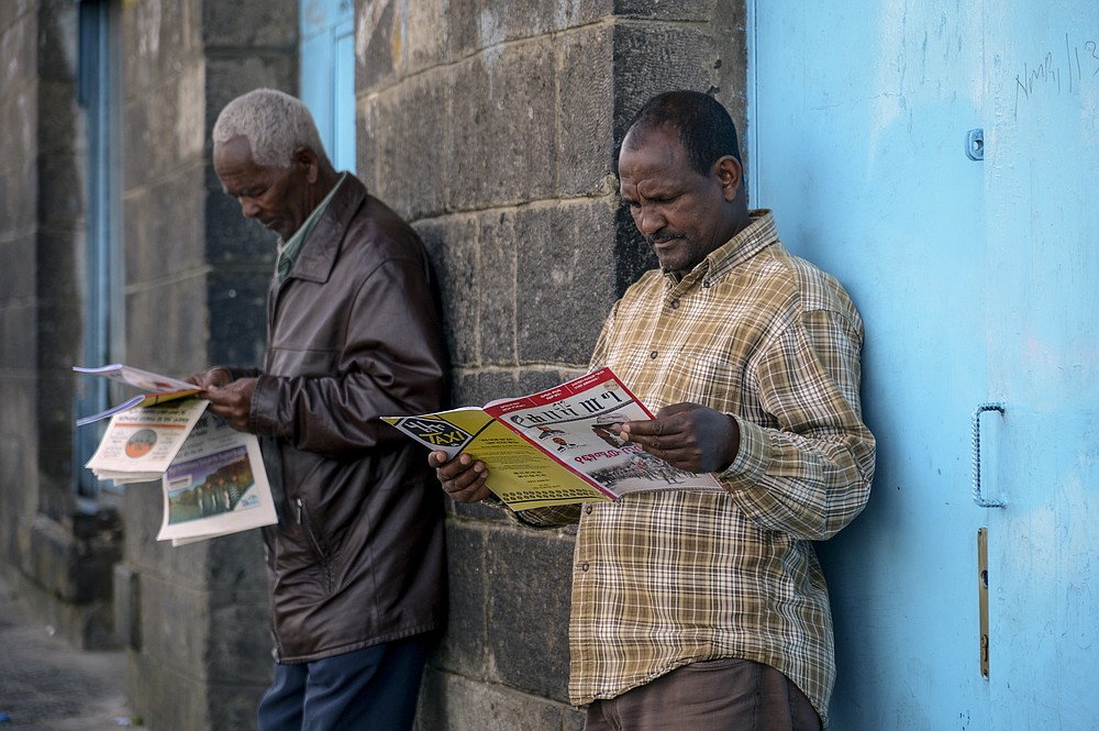 Ethiopians read newspapers and magazines reporting on the current military confrontation in the country, one of which shows a photograph of Prime Minister Abiy Ahmed, on a street in the capital Addis Ababa, Ethiopia Saturday, Nov. 7, 2020. Ethiopia moved Saturday to replace the leadership of the country's defiant northern Tigray region, where deadly clashes between regional and federal government forces are fueling fears the major African power is sliding into civil war. (AP Photo/Samuel Habtab)