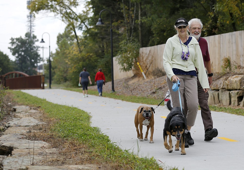 Sheryl and Wayne Pearson walk Meemo (left) and Beretta Thursday, October 8, 2020, as they pick up litter on a new section of trail just south of Sweetbriar Park in Fayetteville. A number of projects related to parks and trails in the city are continuing despite operational budget cuts because of the covid-19 pandemic. Niokaska Creek Trail was unveiled to the public Monday, and stretches from Gulley Park to Sweetbriar Park and connects to Mud Creek Trail to the north. Check out nwaonline.com/201011Daily/ and nwadg.com/photos for a photo gallery.(NWA Democrat-Gazette/David Gottschalk)