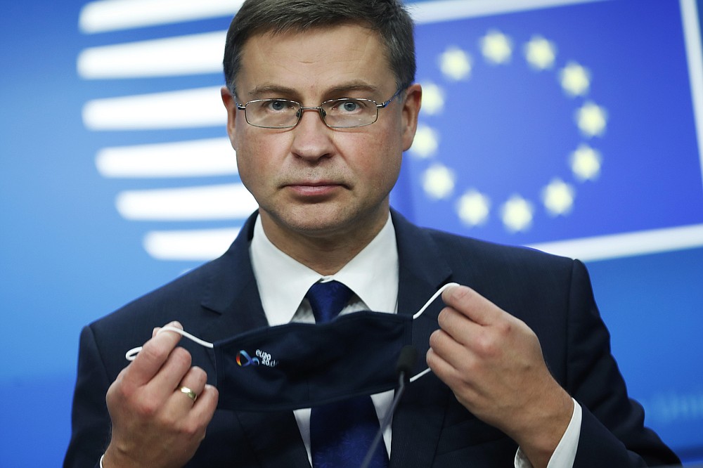 European Commission Vice-President Valdis Dombrovskis takes off his protective face mask prior to addressing a media conference after a meeting of EU trade ministers, in videoconference format, at the European Council building in Brussels, Monday, Nov. 9, 2020. European Union trade ministers on Monday exchanged views on the trade policy review and relations with China and the United States. (AP Photo/Francisco Seco, Pool)