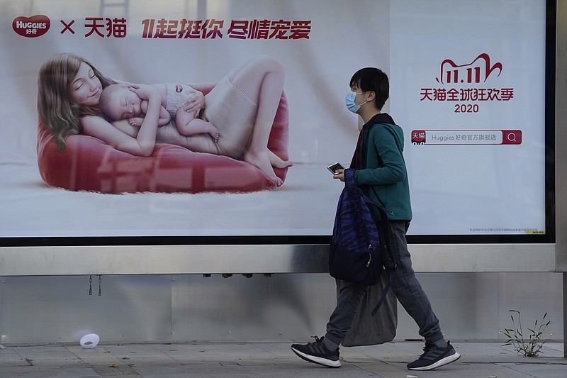 A man wearing a mask to protect from the coronavirus walks past an ad for the Nov. 11 Sales Day in Beijing, China on Oct. 28, 2020. Chinese consumers are expected to spend tens of billions on everything from fresh food to luxury goods during this year's Singles' Day online shopping festival, as the country recovers from the coronavirus pandemic. (AP Photo/Ng Han Guan)