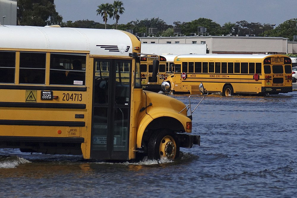 A school bus drives through the flooded parking lot of the Browad School District Central Depot in Oakland Park, Fla., Tuesday, Nov. 10, 2020. Tropical Storm Eta is squatting off western Cuba, and forecasters say it's unclear where it might strike land again. It dumped torrential rain on Cuba and South Florida, flooding entire neighborhoods. (Joe Cavaretta/South Florida Sun-Sentinel via AP)