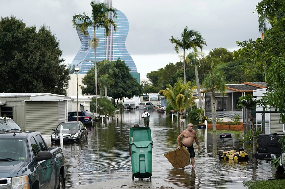 Residents clear debris from a flooded street in the Driftwood Acres Mobile Home Park in the shadow of the Guitar Hotel at Seminole Hard Rock, in the aftermath of Tropical Storm Eta, Tuesday, Nov. 10, 2020, in Davie, Fla. Tropical Storm Eta was squatting off western Cuba on Tuesday after drifting away from South Florida, where it unleashed a deluge that flooded entire neighborhoods and covered the floors of some homes and businesses. (AP Photo/Lynne Sladky)