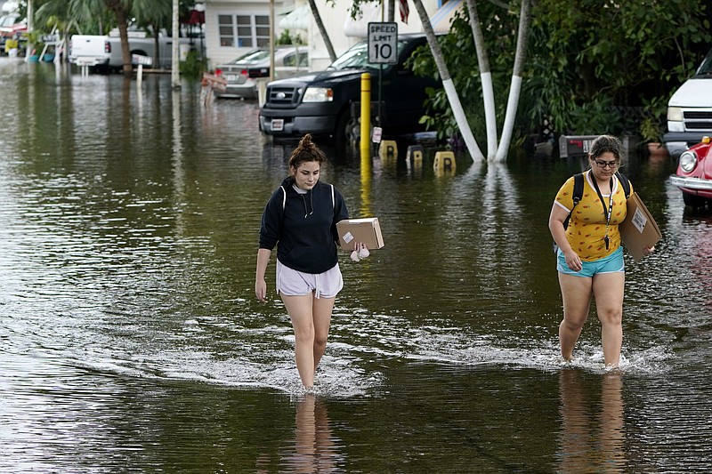 Victoria Rodriguez, left, and Angela Mojica, right, walk on a flooded street in the Driftwood Acres Mobile Home Park, in the aftermath of Tropical Storm Eta, Tuesday, Nov. 10, 2020, in Davie, Fla. Tropical Storm Eta was squatting off western Cuba on Tuesday after drifting away from South Florida, where it unleashed a deluge that flooded entire neighborhoods and covered the floors of some homes and businesses. (AP Photo/Lynne Sladky)