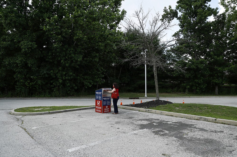 FILE - In this July 1, 2020, file photo, Marianne Carver, of Pennsauken, N.J., drops off her ballot for the New Jersey primary election at a vote-by-mail drop box in a parking lot at Camden County College in Cherry Hill, N.J. The 2020 presidential election had all the makings of a looming disaster: fears of Russian meddling, violence at the polls, voter intimidation and poll workers fleeing their posts over the coronavirus. But the election was largely smooth, in large part because 107 million voters that cast their ballots early and took the pressure off Election Day operations. (AP Photo/Matt Slocum, File)