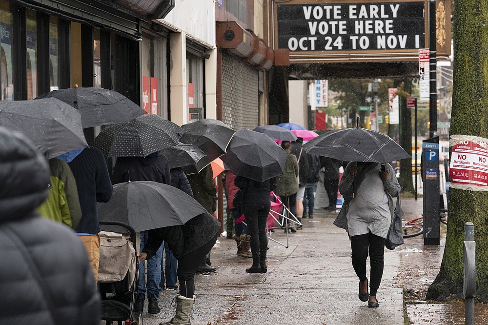 FILE - In this Oct. 30, 2020, file photo, people under umbrellas line up for early voting in the Brooklyn borough of New York. The 2020 presidential election had all the makings of a looming disaster: fears of Russian meddling, violence at the polls, voter intimidation and poll workers fleeing their posts over the coronavirus. But the election was largely smooth, in large part because 107 million voters that cast their ballots early and took the pressure off Election Day operations. (AP Photo/Mark Lennihan, File)