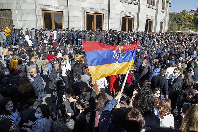 Protesters wave an Armenian national flag during a protest against an agreement to halt fighting over the Nagorno-Karabakh region, in Yerevan, Armenia, Wednesday, Nov. 11, 2020. Thousands of people flooded the streets of Yerevan once again on Wednesday, protesting an agreement between Armenia and Azerbaijan to halt the fighting over Nagorno-Karabakh, which calls for deployment of nearly 2,000 Russian peacekeepers and territorial concessions. Protesters clashed with police, and scores have been detained. (AP Photo/Dmitri Lovetsky)