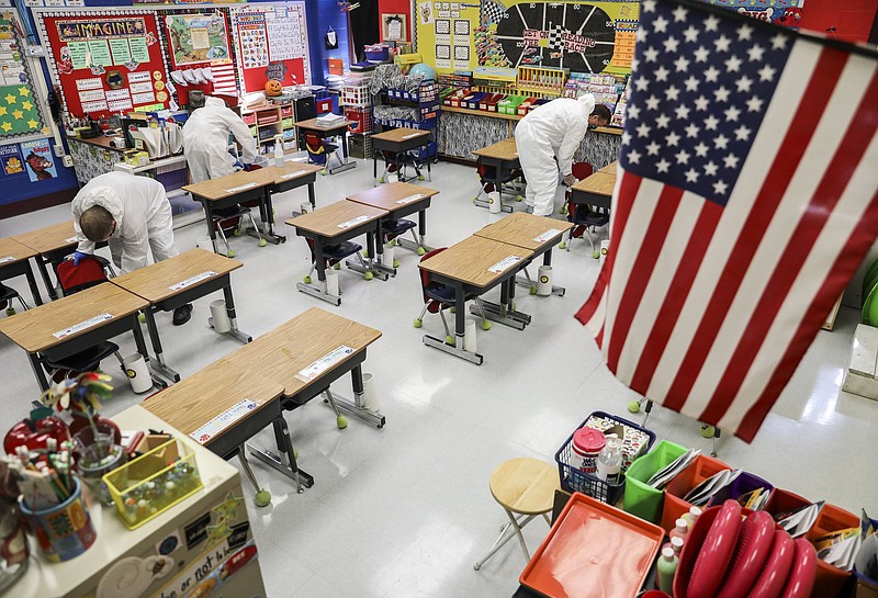 FILE - In this Nov. 5, 2020, file photo, custodial workers clean a classroom at Richard A. Simpson Elementary School in Arnold, Mo. The school went to fully virtual learning on Monday, Nov. 2, after more than 5% of the staff and students tested positive for COVID-19. They will stay virtual at least until Monday, Nov. 16. (Colter Peterson/St. Louis Post-Dispatch via AP, File)