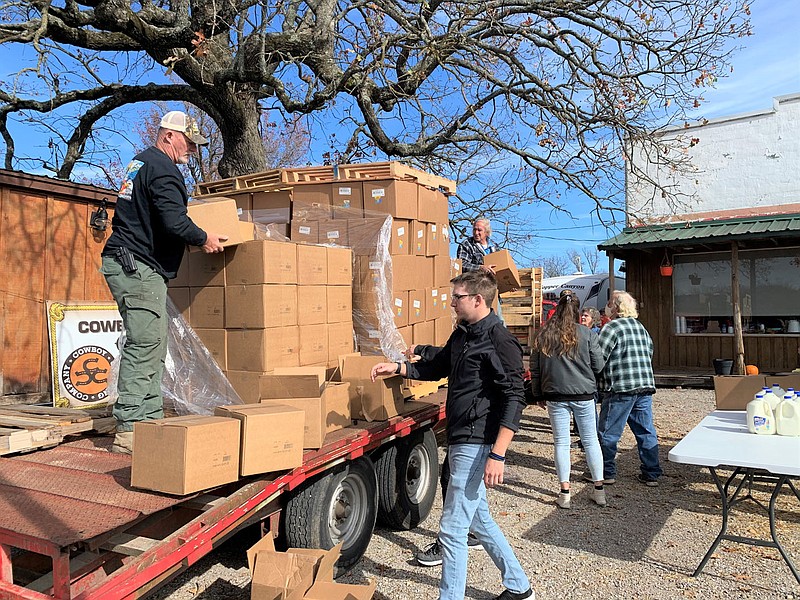 SALLY CARROLL/SPECIAL TO MCDONALD COUNTY PRESS David Jensen, left, gets ready to hand a box to Elijah LeBlanc, as Delbert Roe (back on trailer) works to unload more food items at a local Farmers to Families food box event at Sims Corner Church.