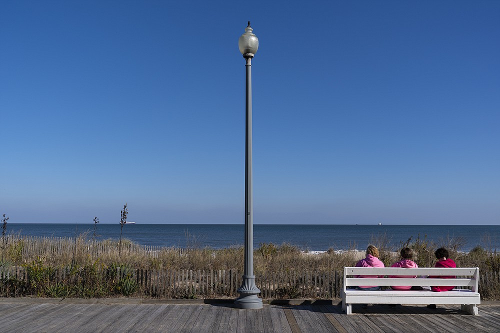 People enjoy a view of the beach, Friday, Nov. 13, 2020, in Rehoboth Beach, Del. This resort town known for Atlantic waves that are sometimes surfable, fresh-cut French fries and a 1-mile wooden boardwalk that dates back to the 1870s has long prided itself on being the “Nation's Summer Capital.” It may soon sport a beach White House. (AP Photo/Alex Brandon)