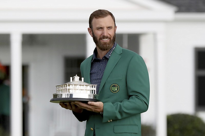 Dustin Johnson holds the trophy after being presented with his first green jacket after winning the Masters golf tournament Sunday, Nov. 15, 2020, in Augusta, Ga. (Curtis Compton/Atlanta Journal-Constitution via AP)