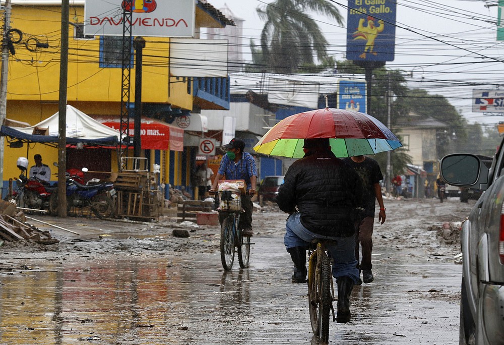 Locals move on street barely cleared from the debris of the last storm, before Hurricane Iota makes landfall in La Lima, Honduras, Monday, November 16, 2020. Hurricane Iota rapidly strengthened Monday into a Category 5 storm that is likely to bring catastrophic damage to the same part of Central America already battered by a powerful Hurricane Eta less than two weeks ago. (AP Photo/Delmer Martinez)
