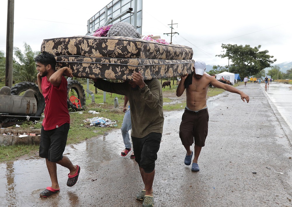 Neighbors help each other as they evacuate the area before Hurricane Iota makes landfall in San Manuel Cortes, Honduras, Monday, November 16, 2020. Hurricane Iota rapidly strengthened into a Category 5 storm that is likely to bring catastrophic damage to the same part of Central America already battered by a powerful Hurricane Eta less than two weeks ago. (AP Photo/Delmer Martinez)