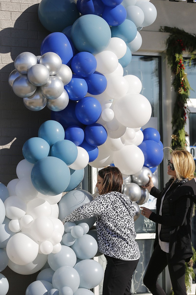 Business partners Marisa Scott (left) and Nikki Lee, with Confetti NWA of Fayetteville, suspend a large balloon garland Tuesday, November 17, 2020, on the storefront of Linden's Jewelry. Linden's is celebrating a grand re-opening after relocating their store from Bella Vista to Bentonville. Check out nwaonline.com/201118Daily/ and nwadg.com/photos for a photo gallery.(NWA Democrat-Gazette/David Gottschalk)