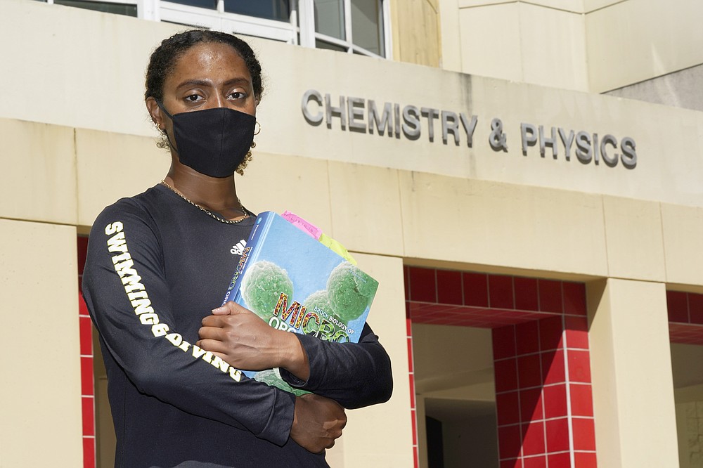 Kelsie Campbell, a student at Florida International University in Miami, poses for a photo on campus, Thursday, Oct. 8, 2020. When Campbell, who is part Jamaican and part British, heard in both the British and American media that Black and ethnic minorities were being disproportionately hurt by the pandemic, she wanted to focus on why. (AP Photo/Wilfredo Lee)