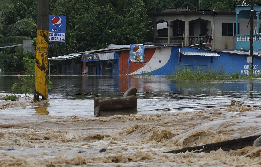 A chair sits in a flooded road after the passing of Iota in La Lima, Honduras, Wednesday, Nov. 18, 2020. Iota flooded stretches of Honduras still underwater from Hurricane Eta, after it hit Nicaragua Monday evening as a Category 4 hurricane and weakened as it moved across Central America, dissipating over El Salvador early Wednesday. (AP Photo/Delmer Martinez)