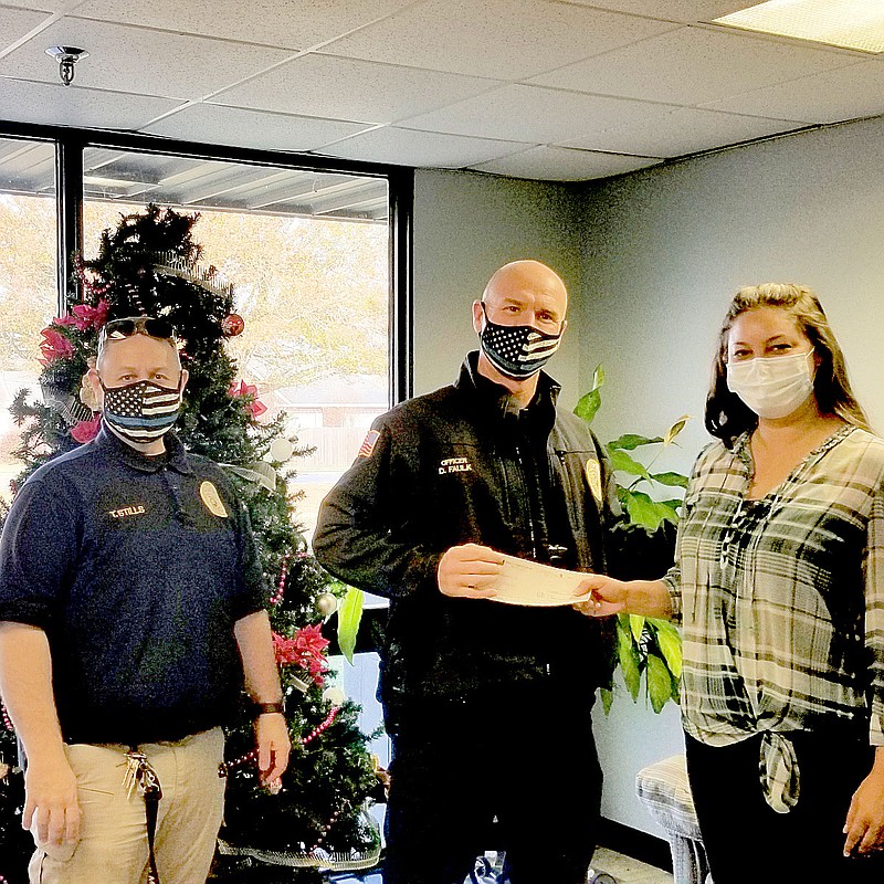 SUBMITTED PHOTO
Brandy Allen with Specialty Fastening Systems in Prairie Grove donates to School Resource Officers Travis Stills, left, and David Faulk for the Prairie Grove Police Department's Shop with a Cop Program. The department is still accepting donations for this year's program. There are about 60 children on this year's list.