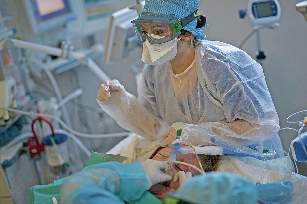 Nurses clean and adjust an endotracheal tube providing respiratory assistance to a 61-year-old COVID-19 patient at the ICU in the La Timone hospital in Marseille, southern France, Thursday, Nov. 12, 2020. In Marseille the second wave of the coronavirus is bringing even more people to the ICU than the first one in the spring, many in more severe condition. (AP Photo/Daniel Cole)