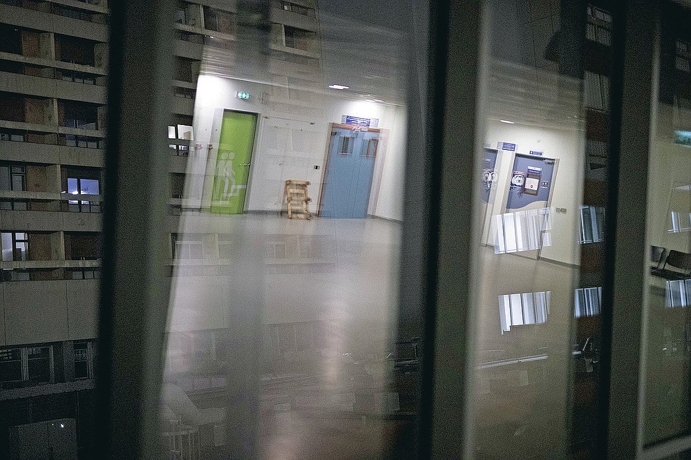 Illuminated hospital rooms are can be seen through the reflection of a vacant corridor during the night shift at the La Timone hospital in Marseille, southern France, Friday, Nov. 13, 2020. In Marseille the second wave of the coronavirus is bringing even more people to the ICU than the first one in the spring, many in more severe condition. (AP Photo/Daniel Cole)