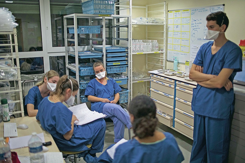 At the end of her shift, 26-year-old Nurse Pauline Reynier, center left, updates the night shift nurses on the statuses of COVID-19 patients in a makeshift ICU at the La Timone hospital in Marseille, southern France, Thursday, Nov. 12, 2020. (AP Photo/Daniel Cole)