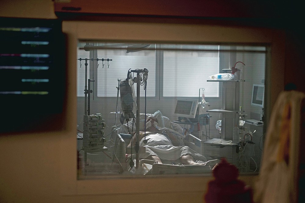 A 60-year-old COVID-19 patient is pictured through the window of an ICU room at the La Timone hospital in Marseille, southern France, Thursday, Nov. 12, 2020. (AP Photo/Daniel Cole)