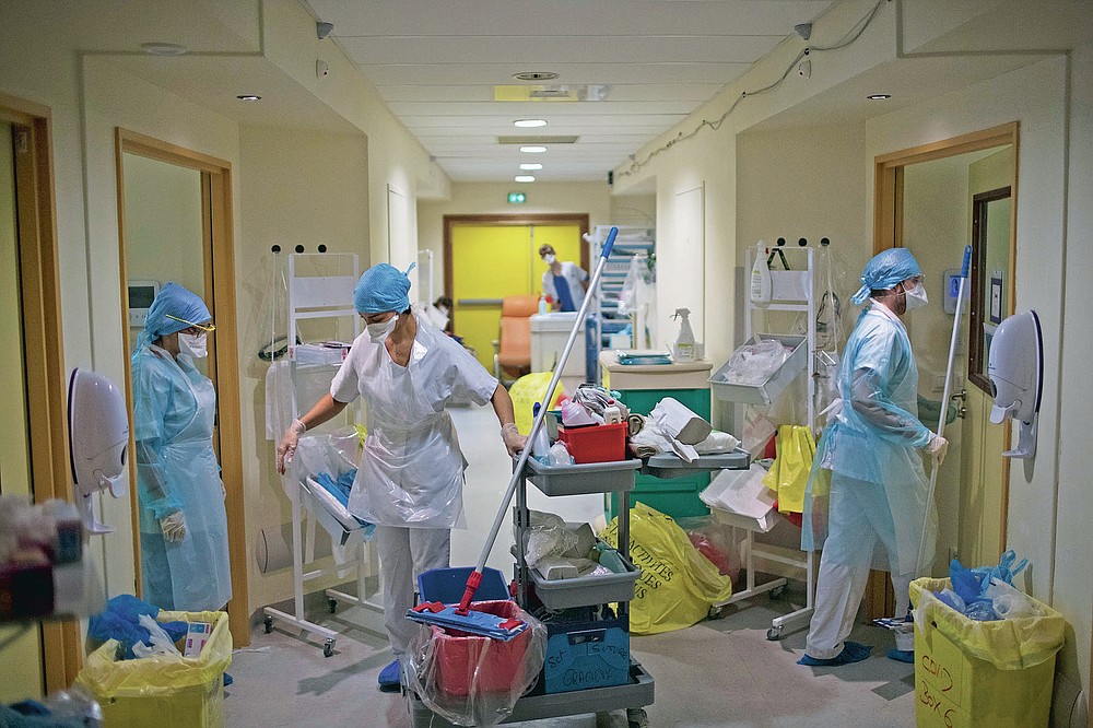 Medical workers wearing protective layers of plastic prepare to clean rooms in the hallway of a makeshift ICU at the La Timone hospital in Marseille, southern France, Thursday, Nov. 12, 2020. (AP Photo/Daniel Cole)