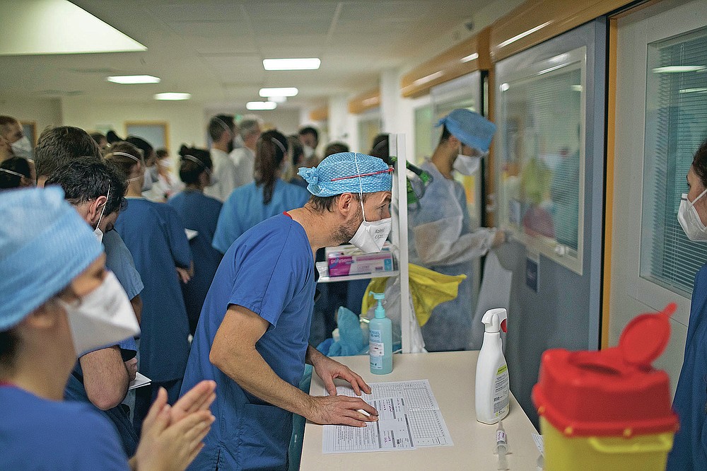 A medical worker peers through the glass of an ICU room containing a COVID-19 patient at the La Timone hospital in Marseille, southern France, Thursday, Nov. 12, 2020. (AP Photo/Daniel Cole)